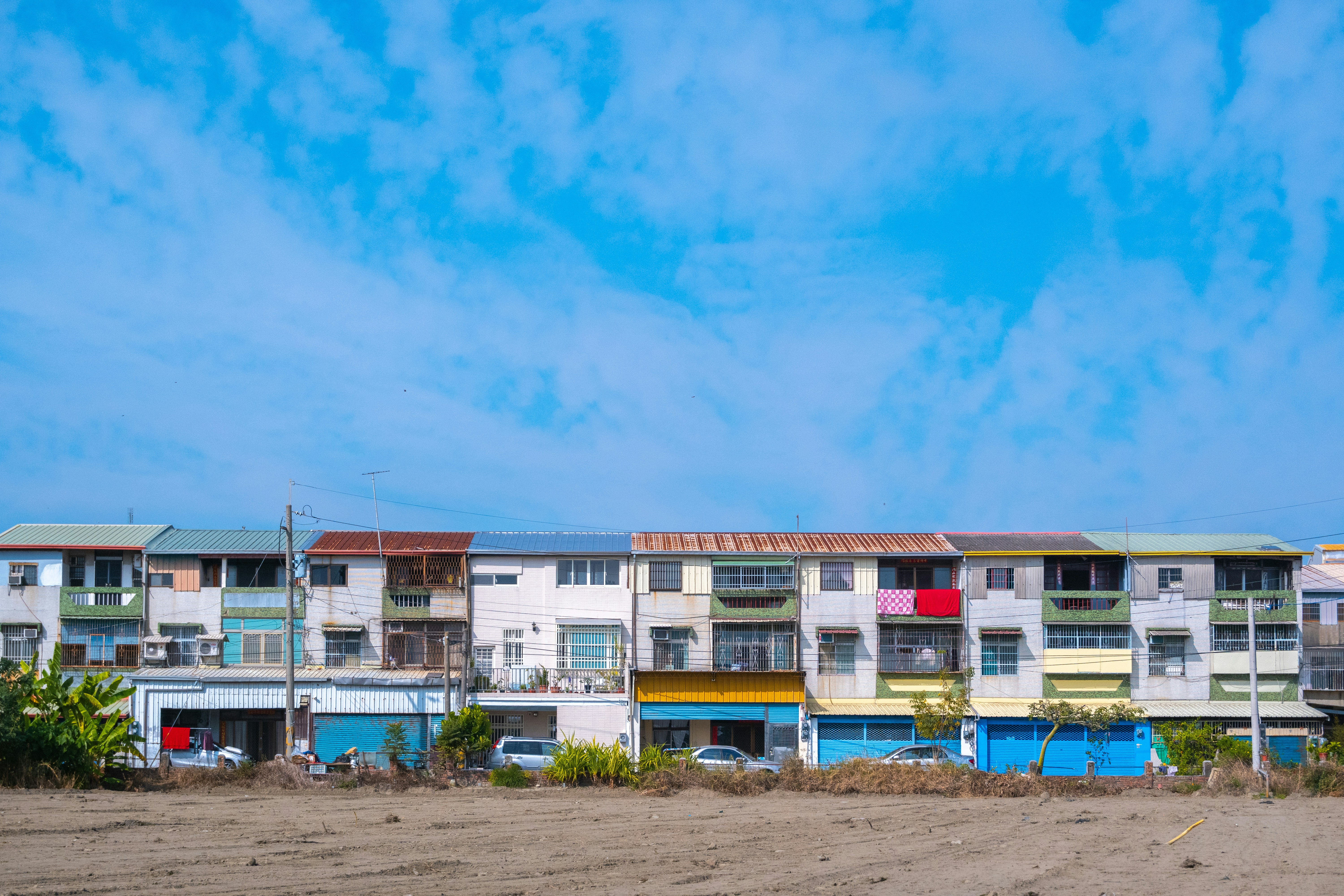 a row of multi - colored buildings sitting on top of a sandy beach