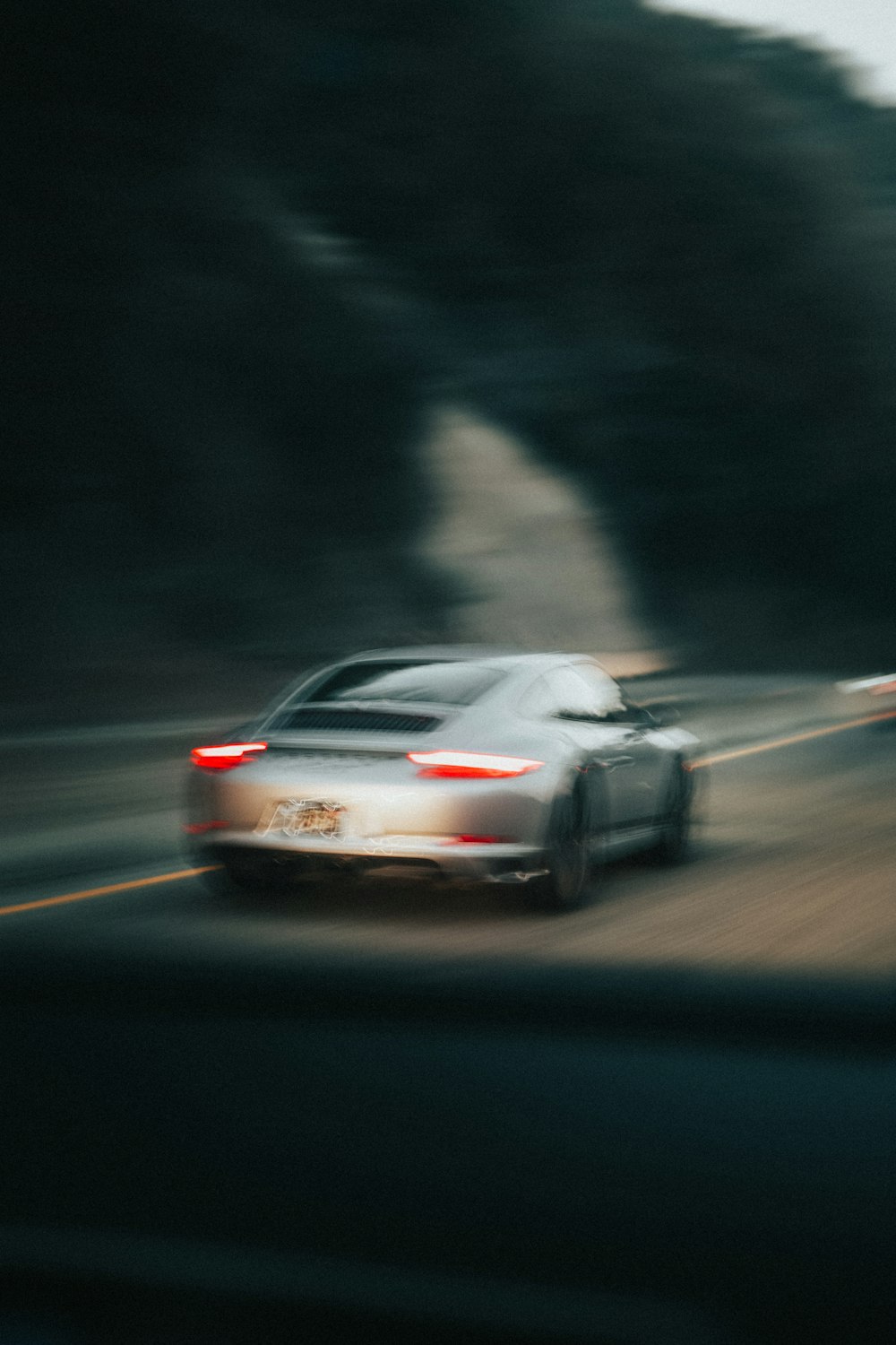 a car driving down a road next to a forest