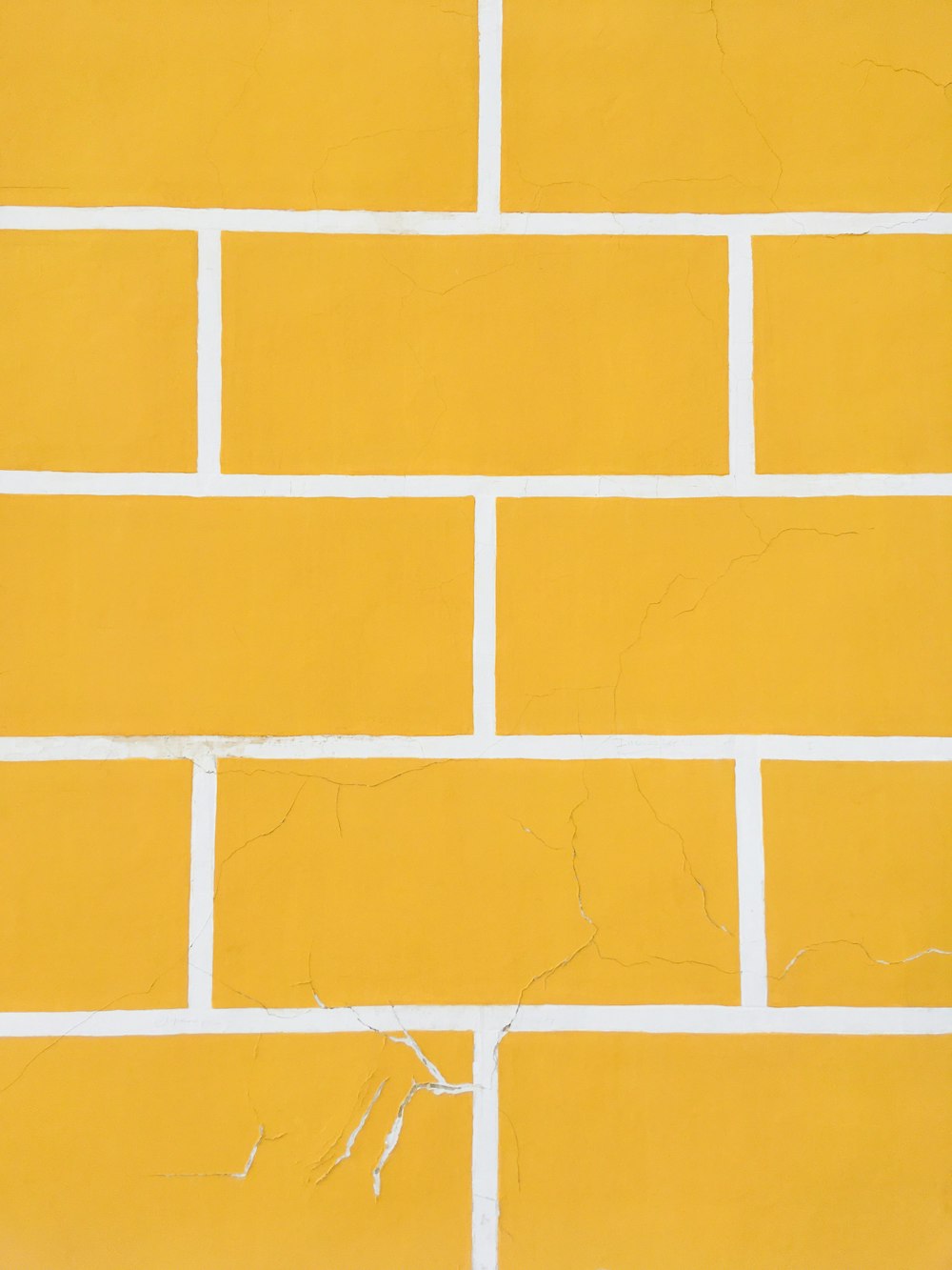 a yellow brick wall with white paint on it