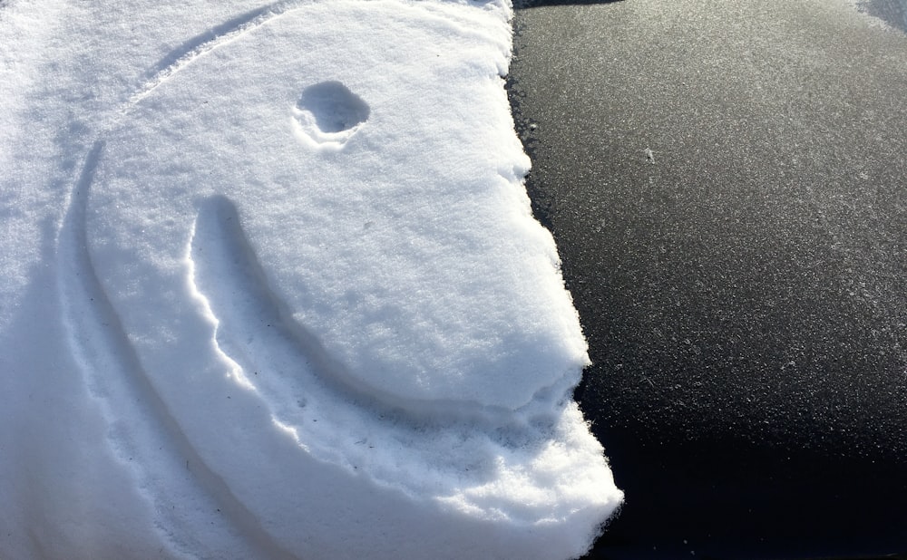 a car covered in snow with a smiley face drawn on it
