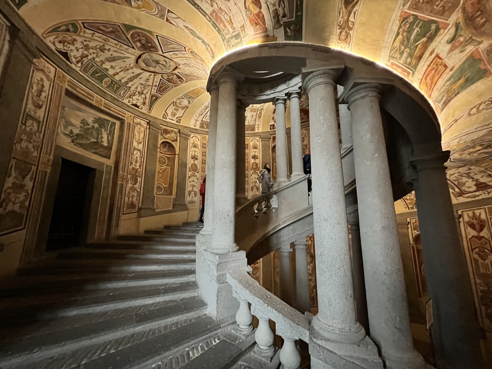 a spiral staircase in a building with paintings on the walls