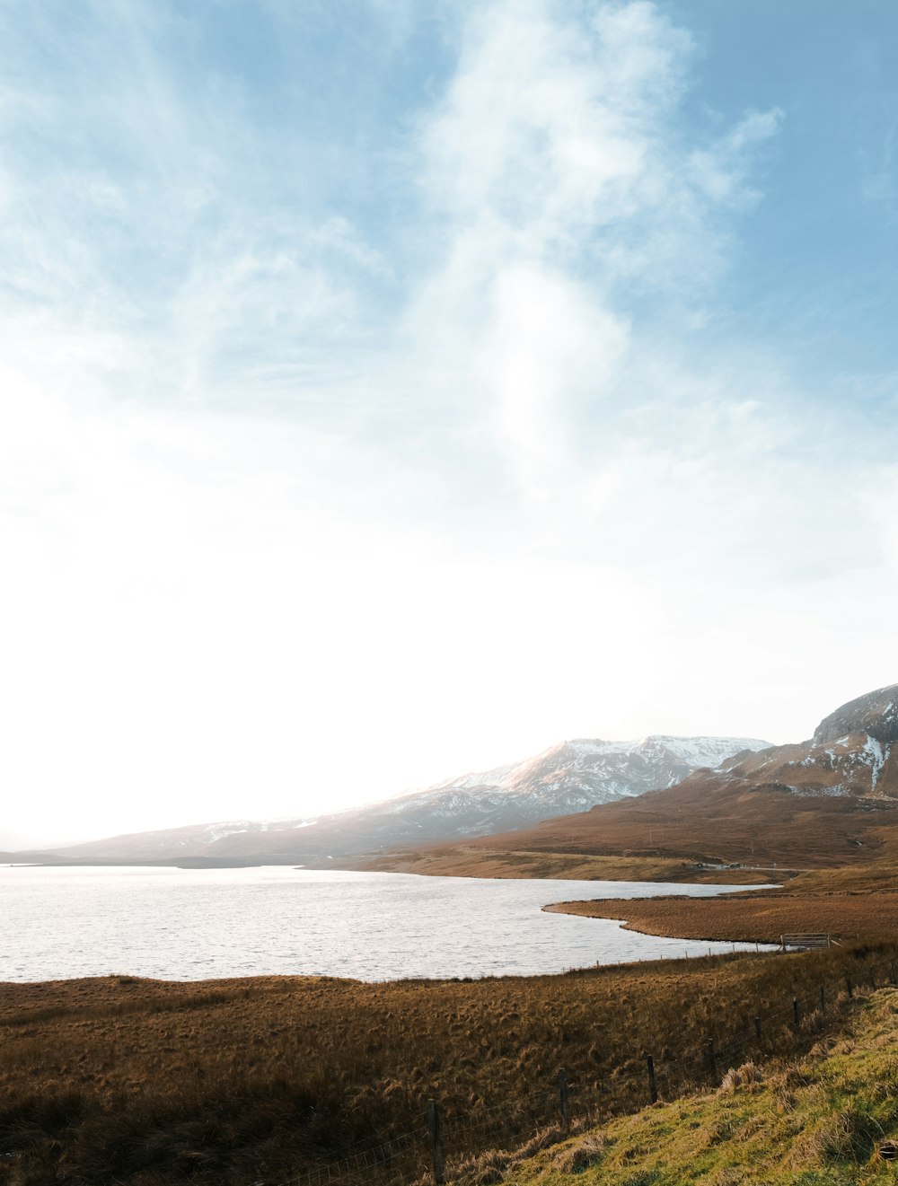 a large body of water sitting next to a lush green hillside