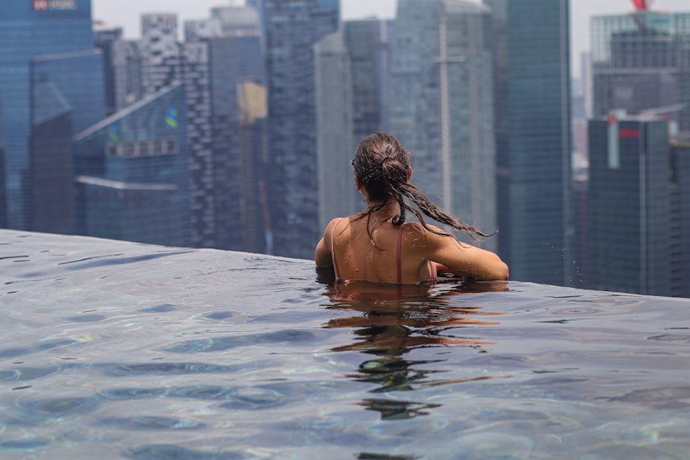 a woman is sitting in the water of a swimming pool