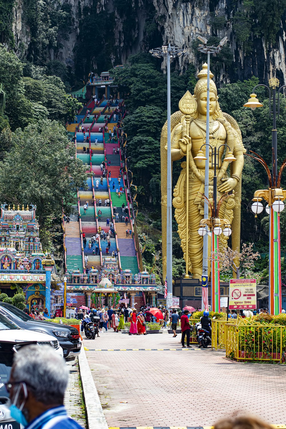 a group of people walking down a street next to a giant statue