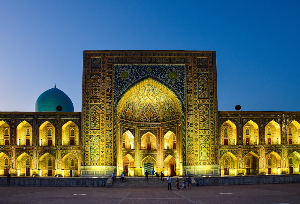 a building lit up at night with people standing in front of it