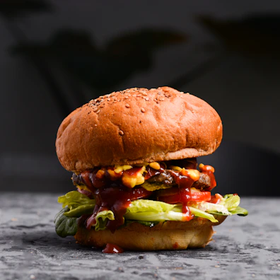 A juicy hamburger with melted cheese and crispy lettuce on a vibrant background.