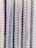Rows of metallic, cylindrical tubes stacked vertically with a reflective surface that gives off a shiny appearance. The tubes are wrapped in a thin, translucent plastic cover.