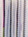Rows of metallic, cylindrical tubes stacked vertically with a reflective surface that gives off a shiny appearance. The tubes are wrapped in a thin, translucent plastic cover.