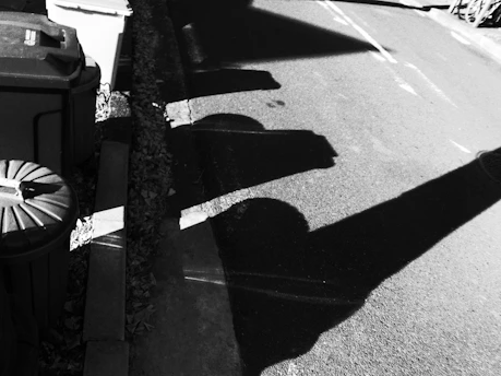 A striking black and white street scene captured with a Ricoh GR camera, showcasing deep shadows and crisp highlights.