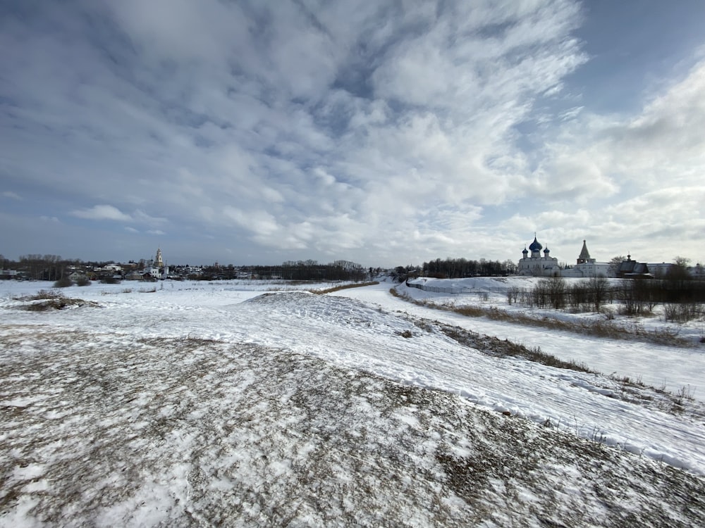 a snow covered field with a church in the distance