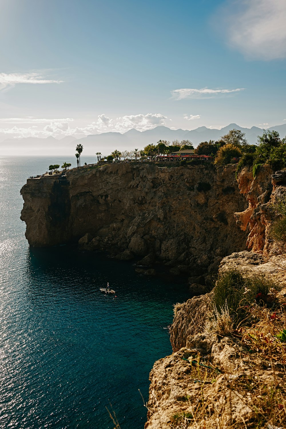 a boat is on the water near a cliff