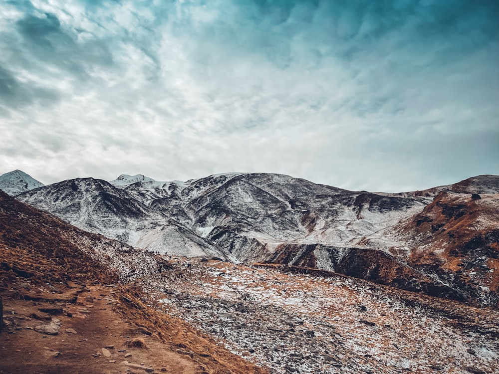 a snow covered mountain range under a cloudy sky