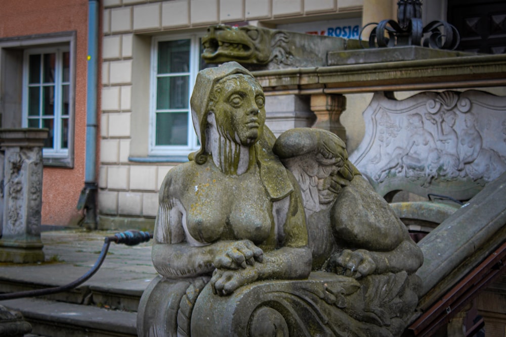 Una estatua de una mujer sentada encima de un banco