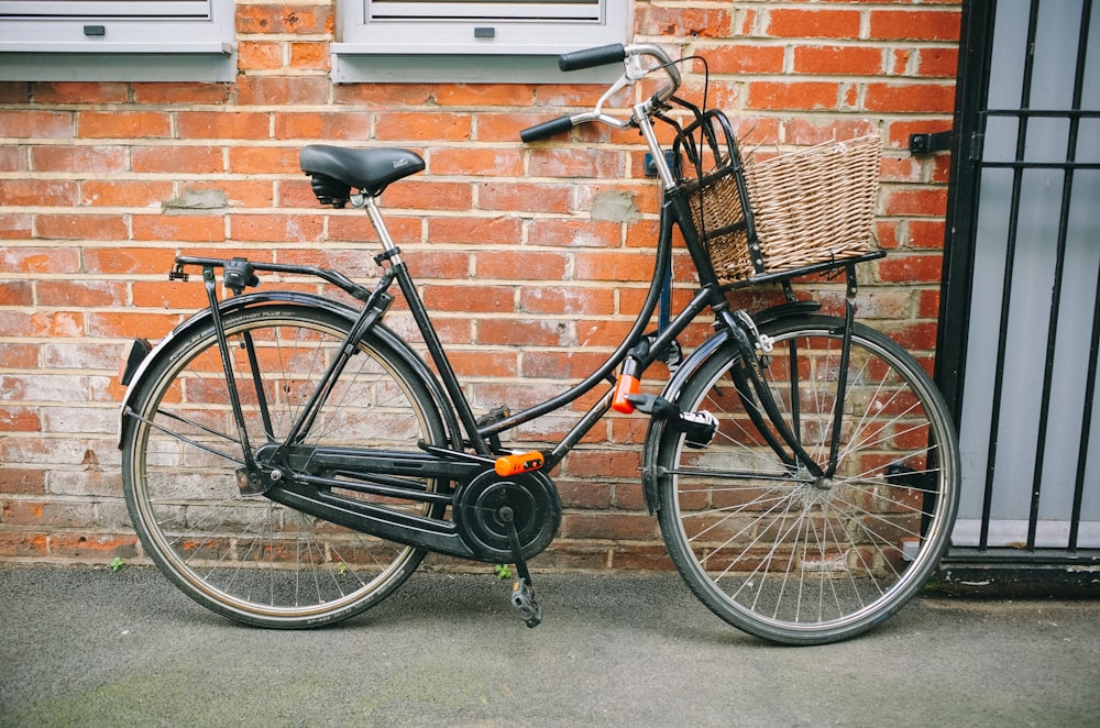 a bicycle parked next to a brick wall