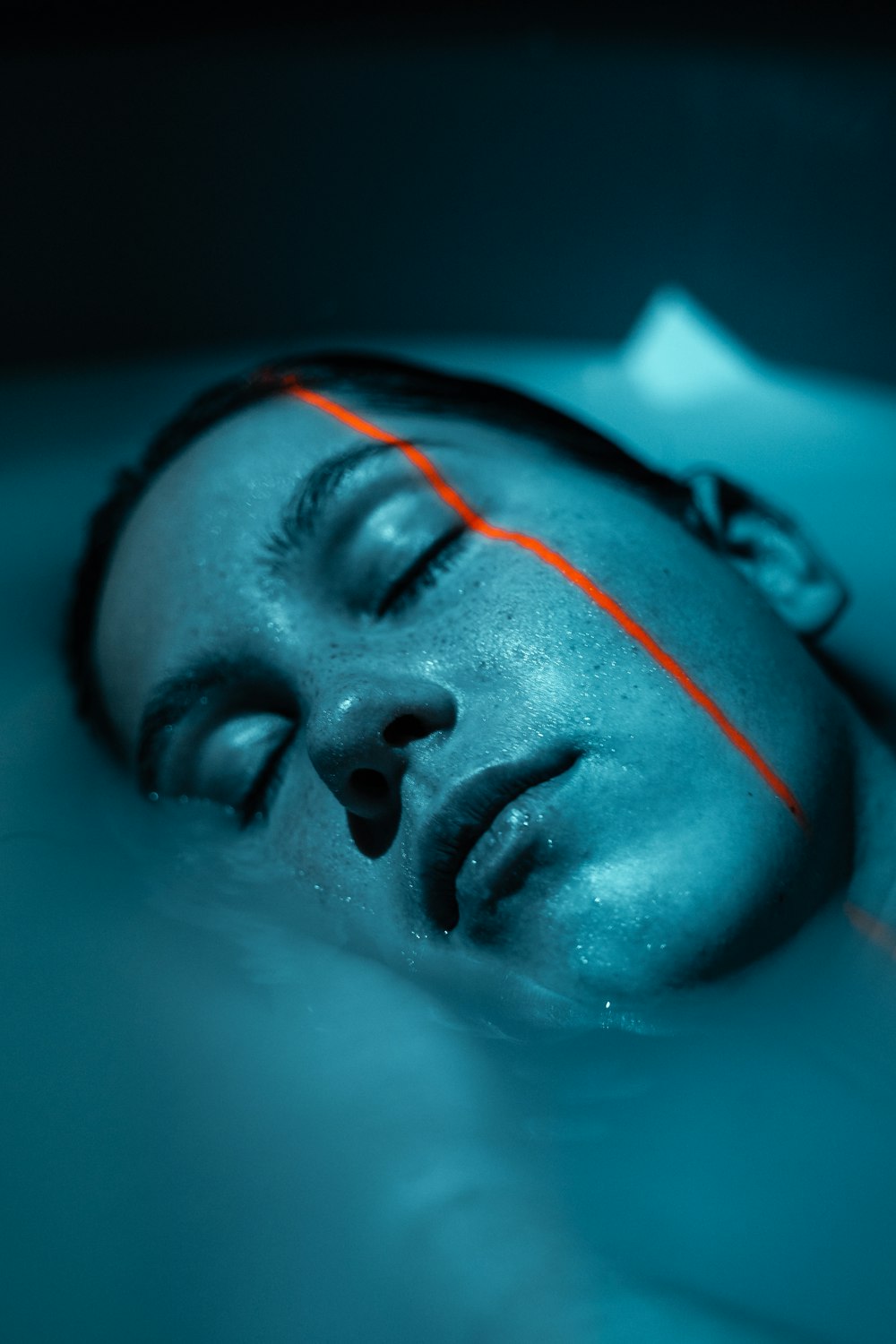 a man laying in the water with his eyes closed