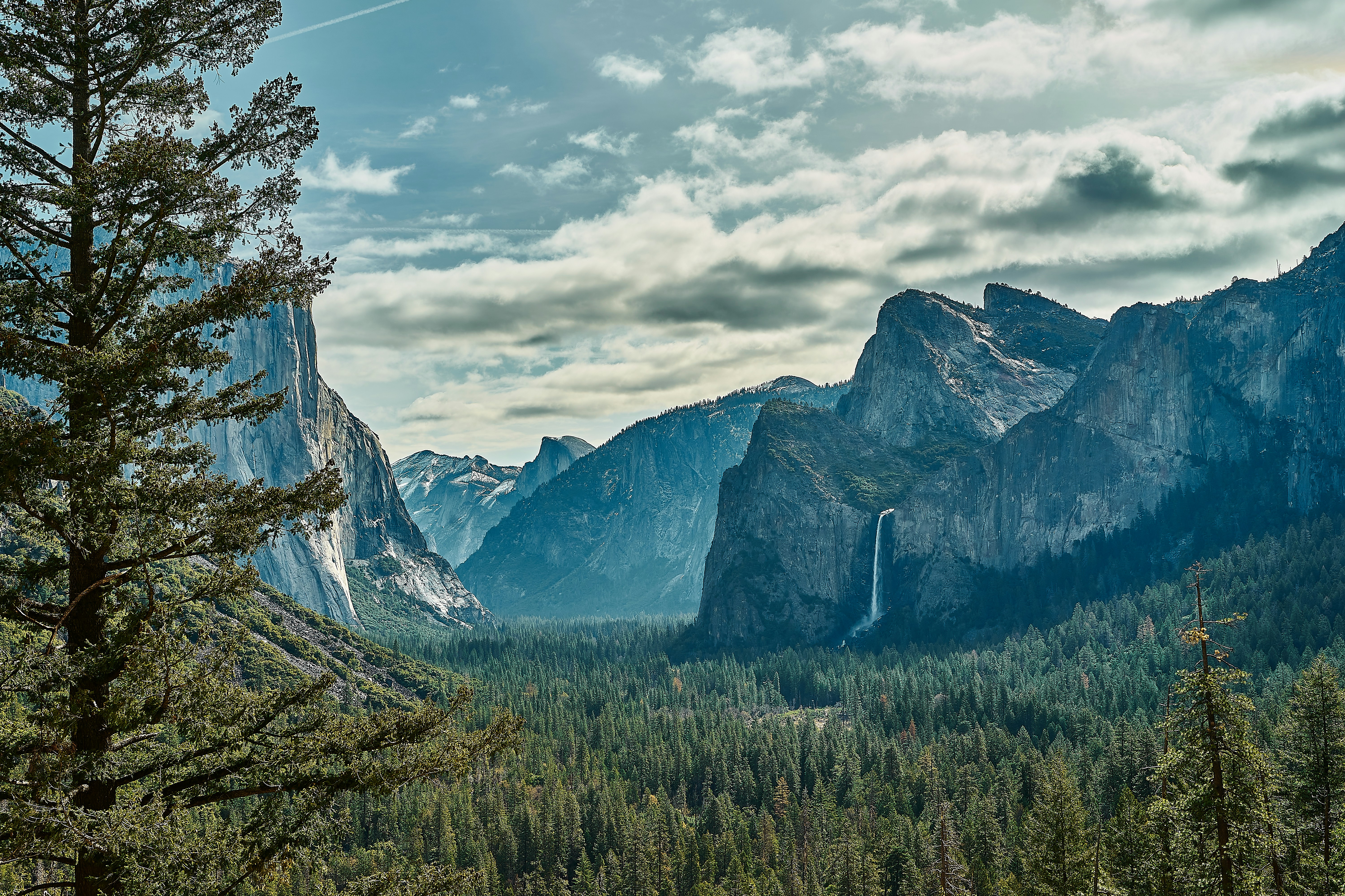 a scenic view of mountains and trees with a cloudy sky