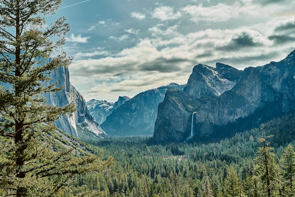 a scenic view of mountains and trees with a cloudy sky