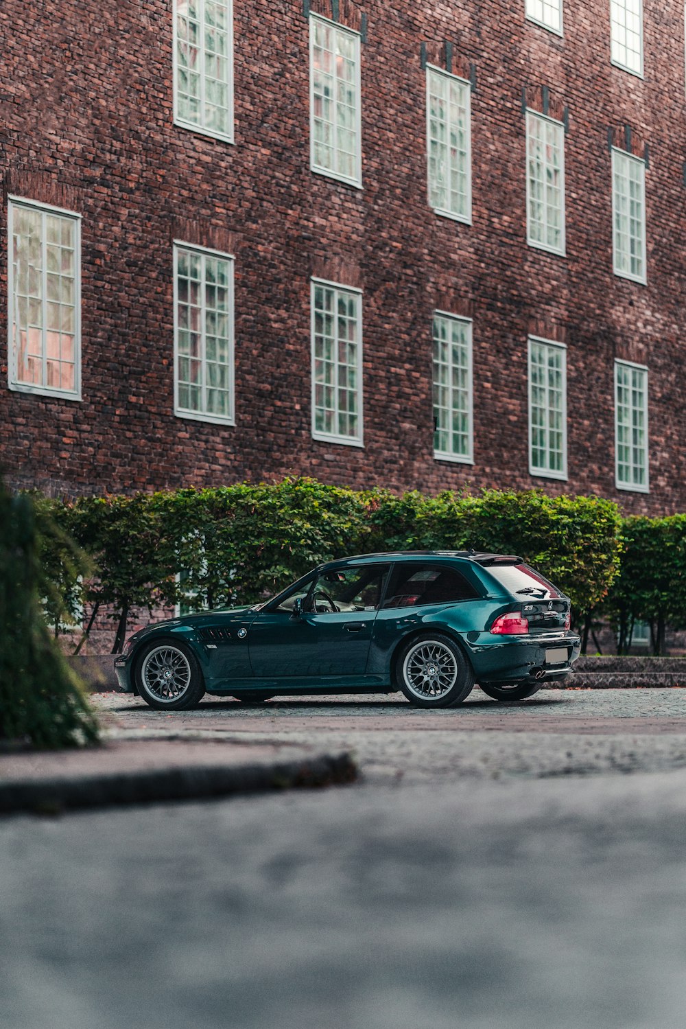a green car parked in front of a brick building