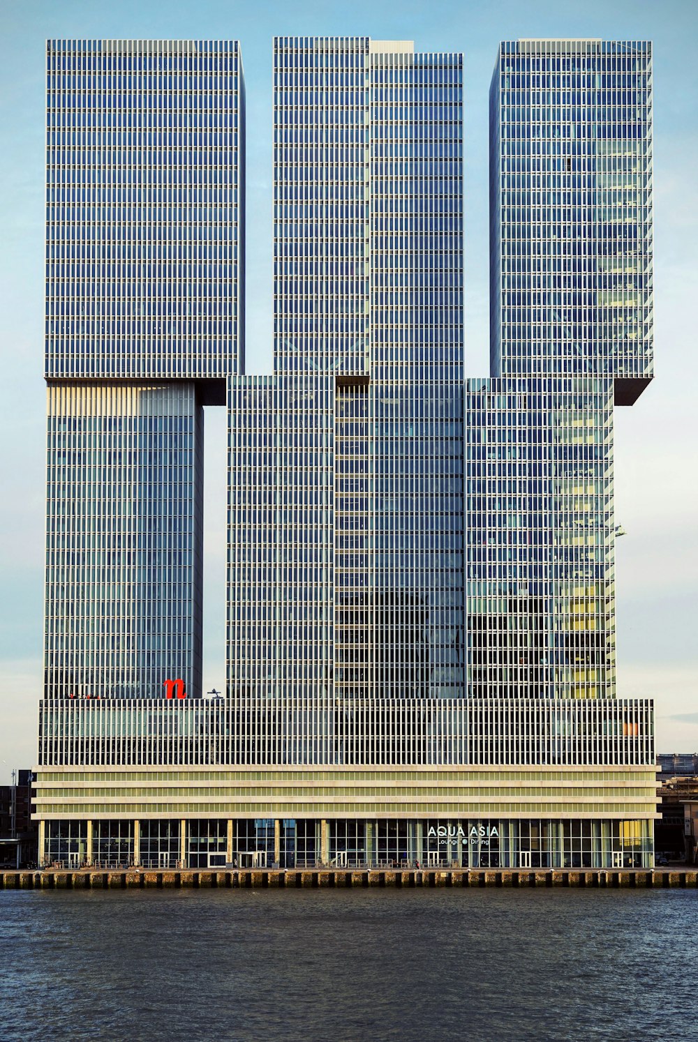 two tall buildings sitting next to each other on top of a body of water