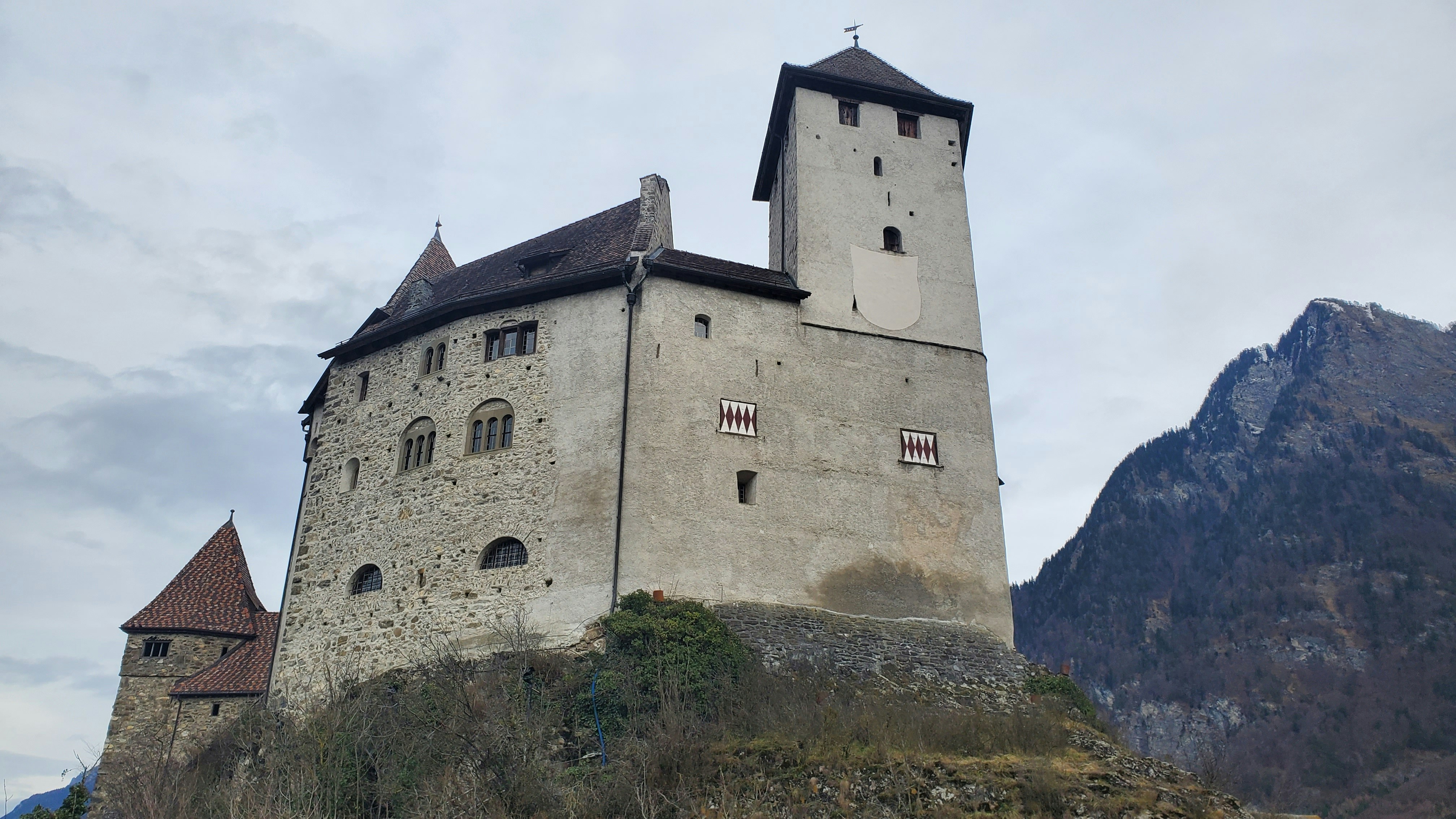 a castle on a hill with mountains in the background, 
