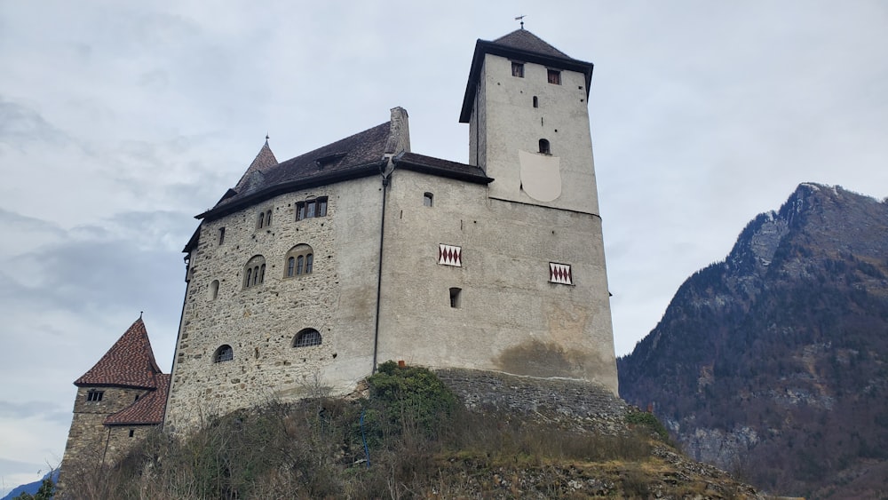 a castle on a hill with mountains in the background