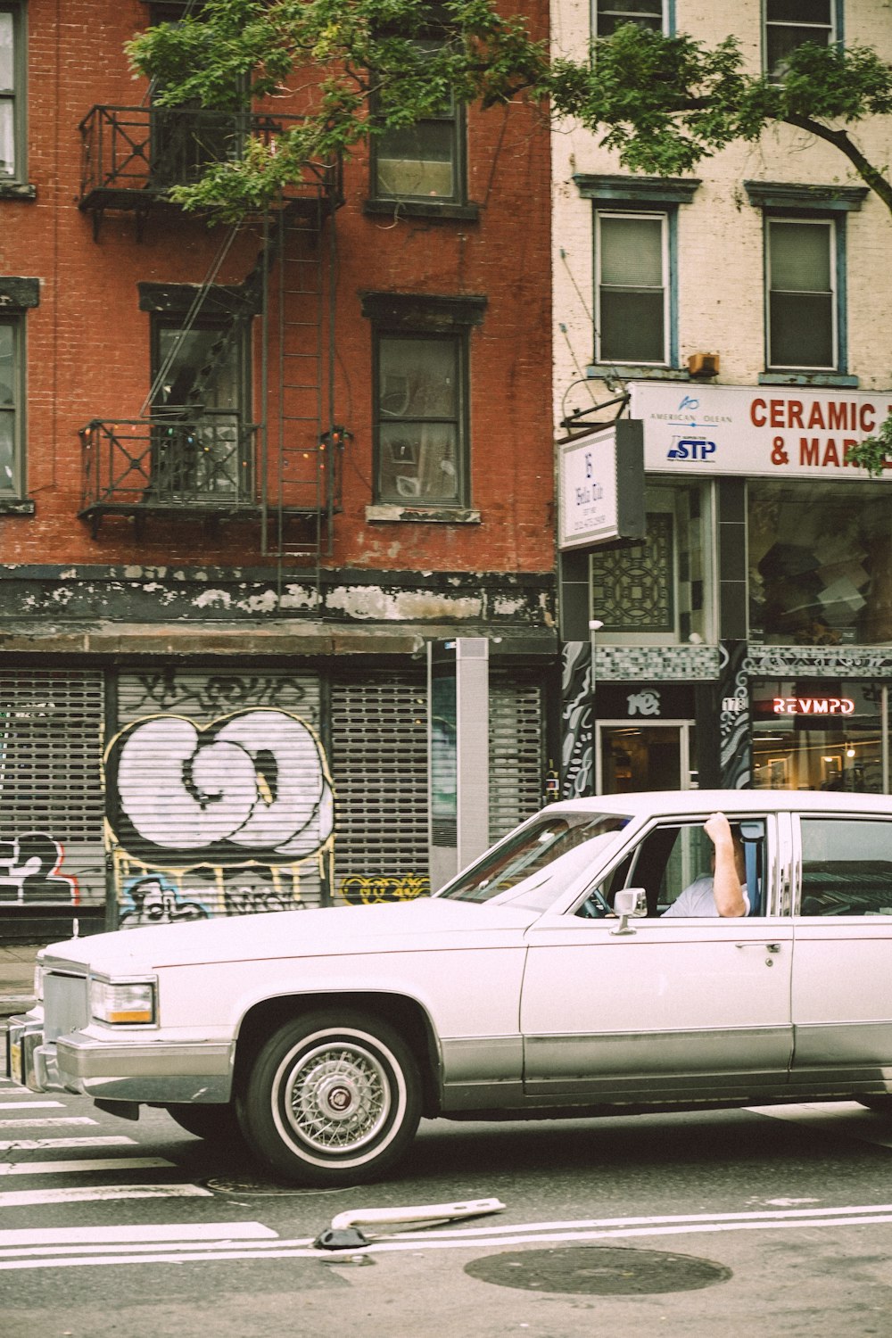 a white car driving down a street next to tall buildings