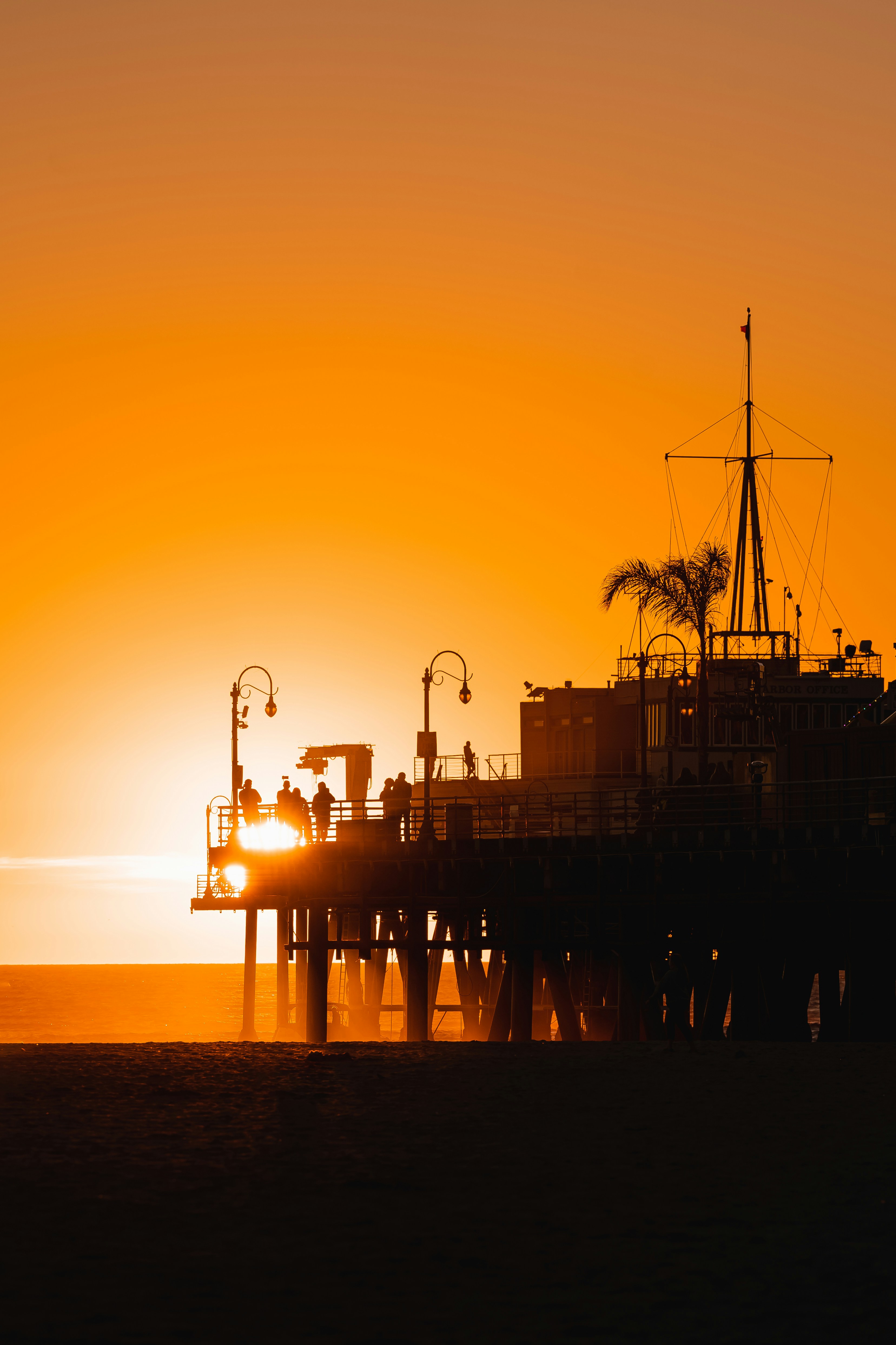 the sun is setting over a pier with a boat in the water