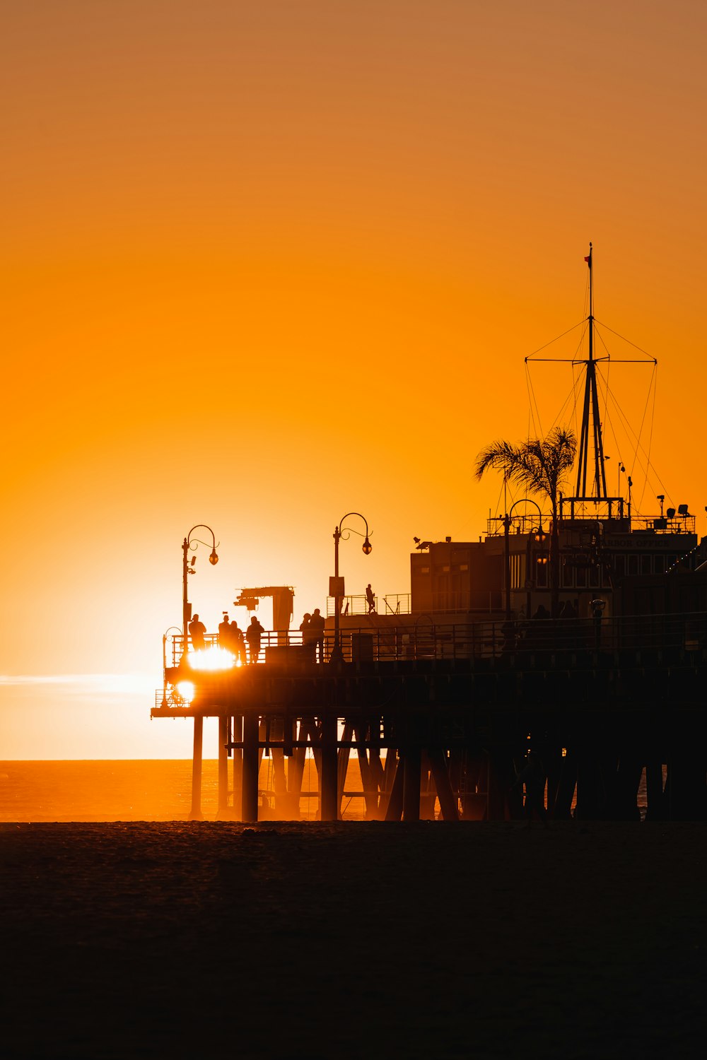 the sun is setting over a pier with a boat in the water