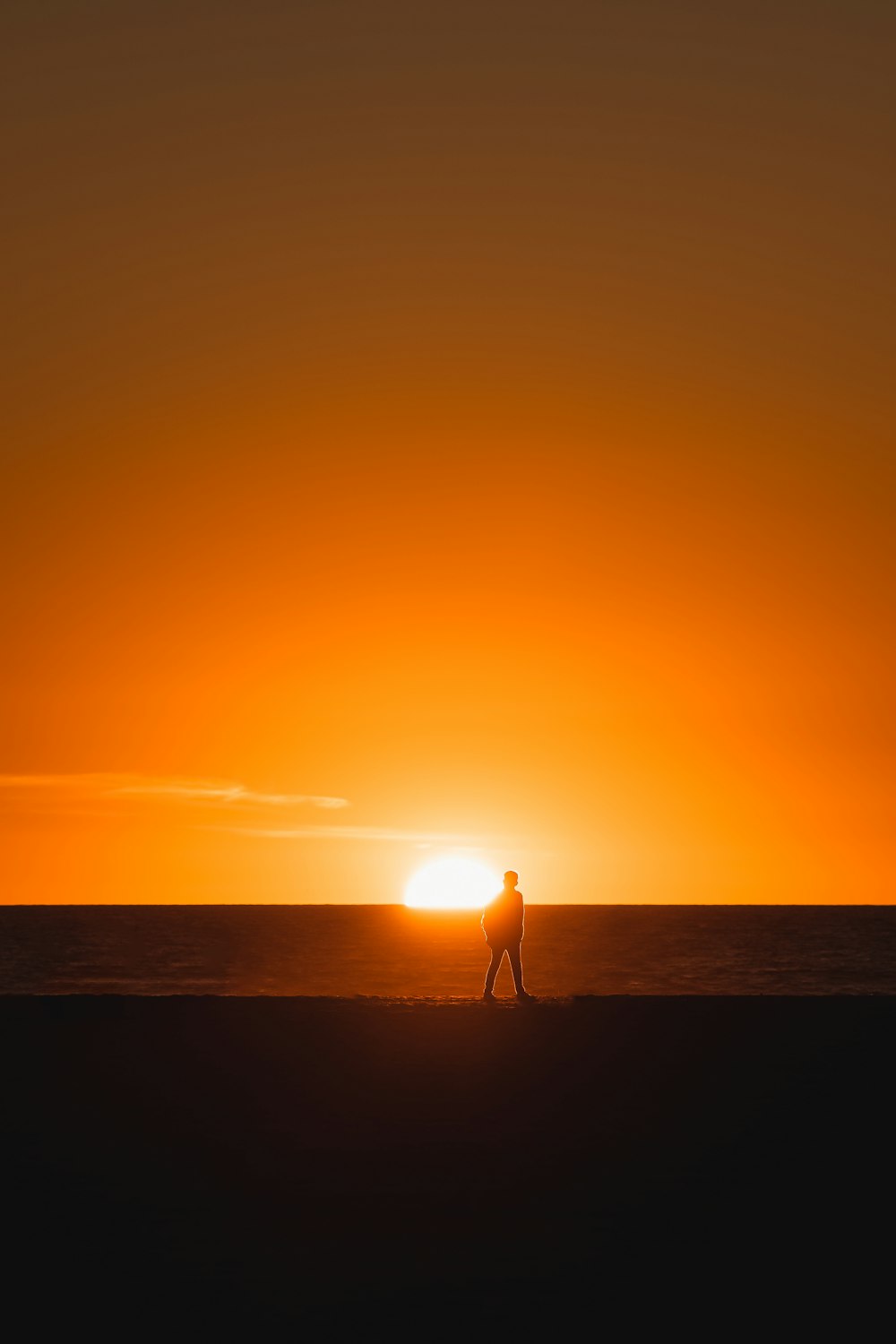 a person walking on a beach at sunset