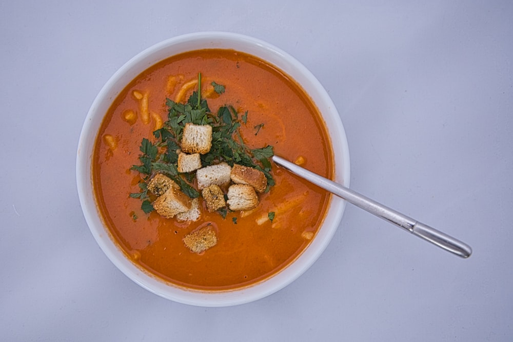 a bowl of tomato soup with croutons and spinach