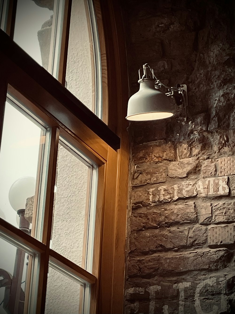 a light hanging from a brick wall next to a window