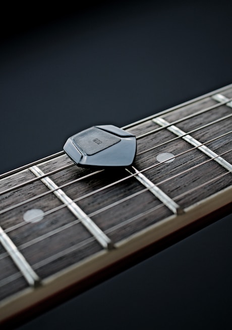 A close-up of a guitar with worn strings resting against a stack of lyric notebooks.