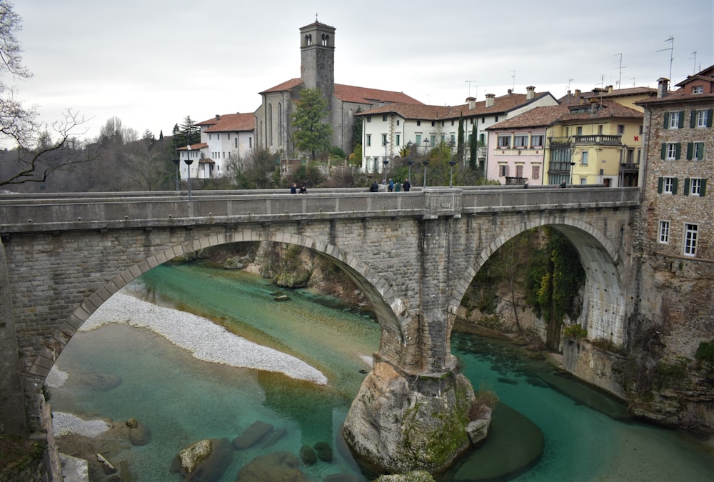 a stone bridge over a river with buildings in the background
