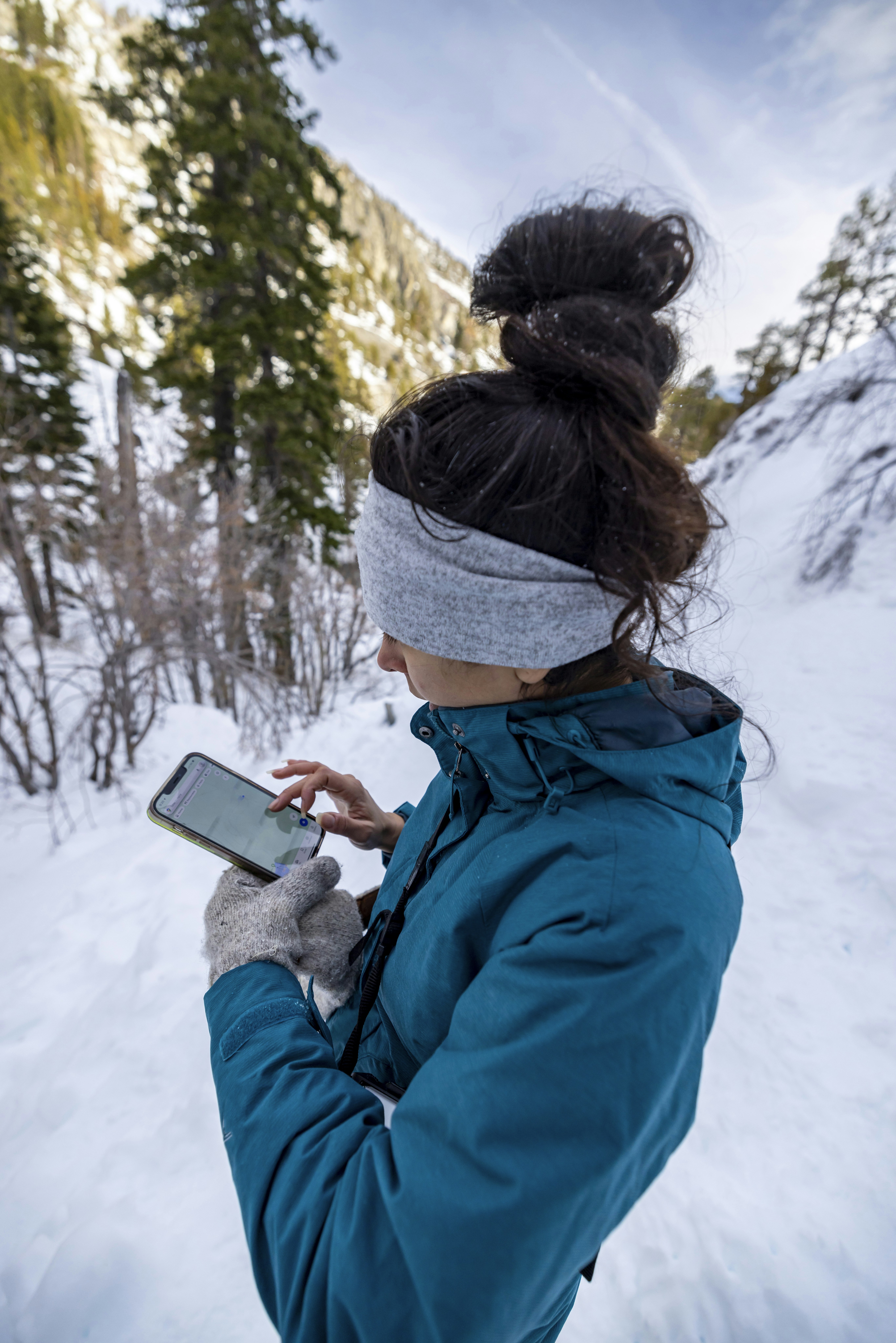 a woman standing in the snow looking at her cell phone