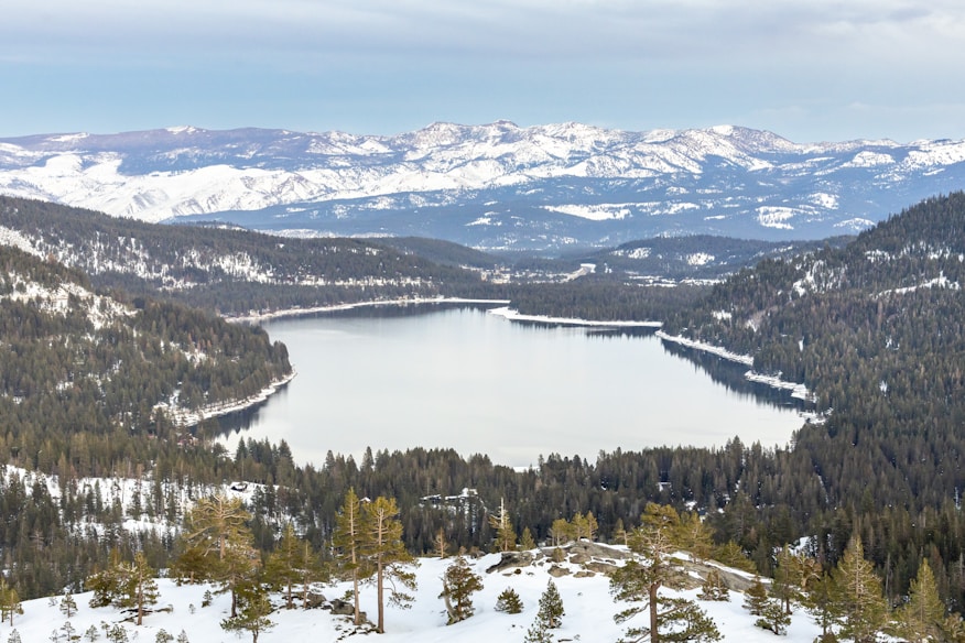 a view of a lake surrounded by snow covered mountains