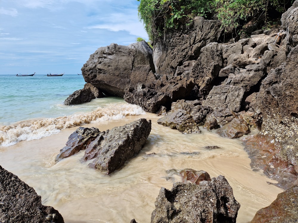 a beach with rocks and a boat in the water