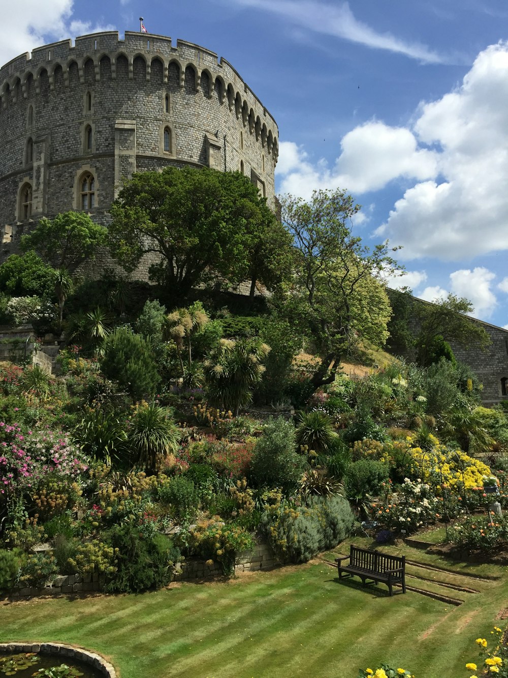 a castle with a garden and a bench in front of it