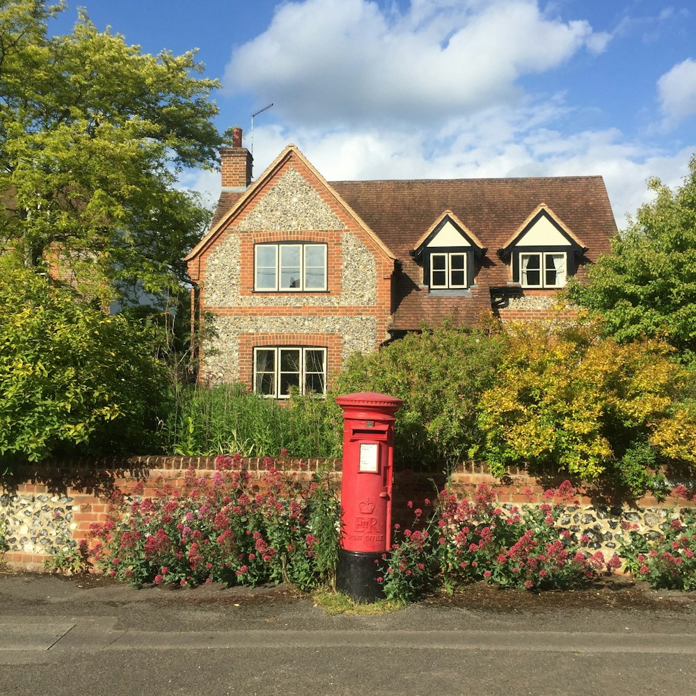 a red mailbox in front of a brick house