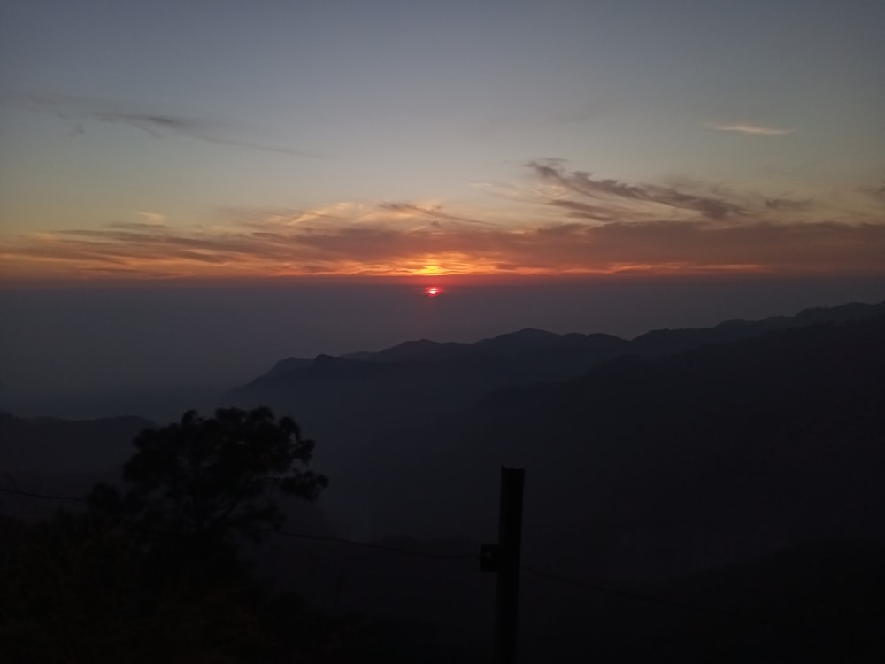 the sun is setting over a mountain range