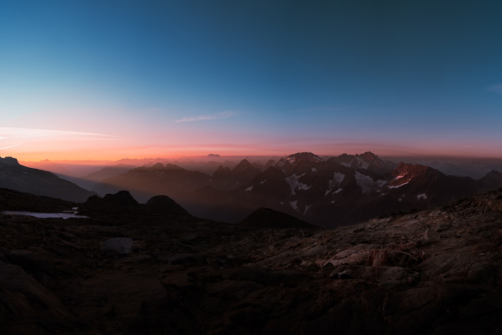 the sun is setting over a mountain range