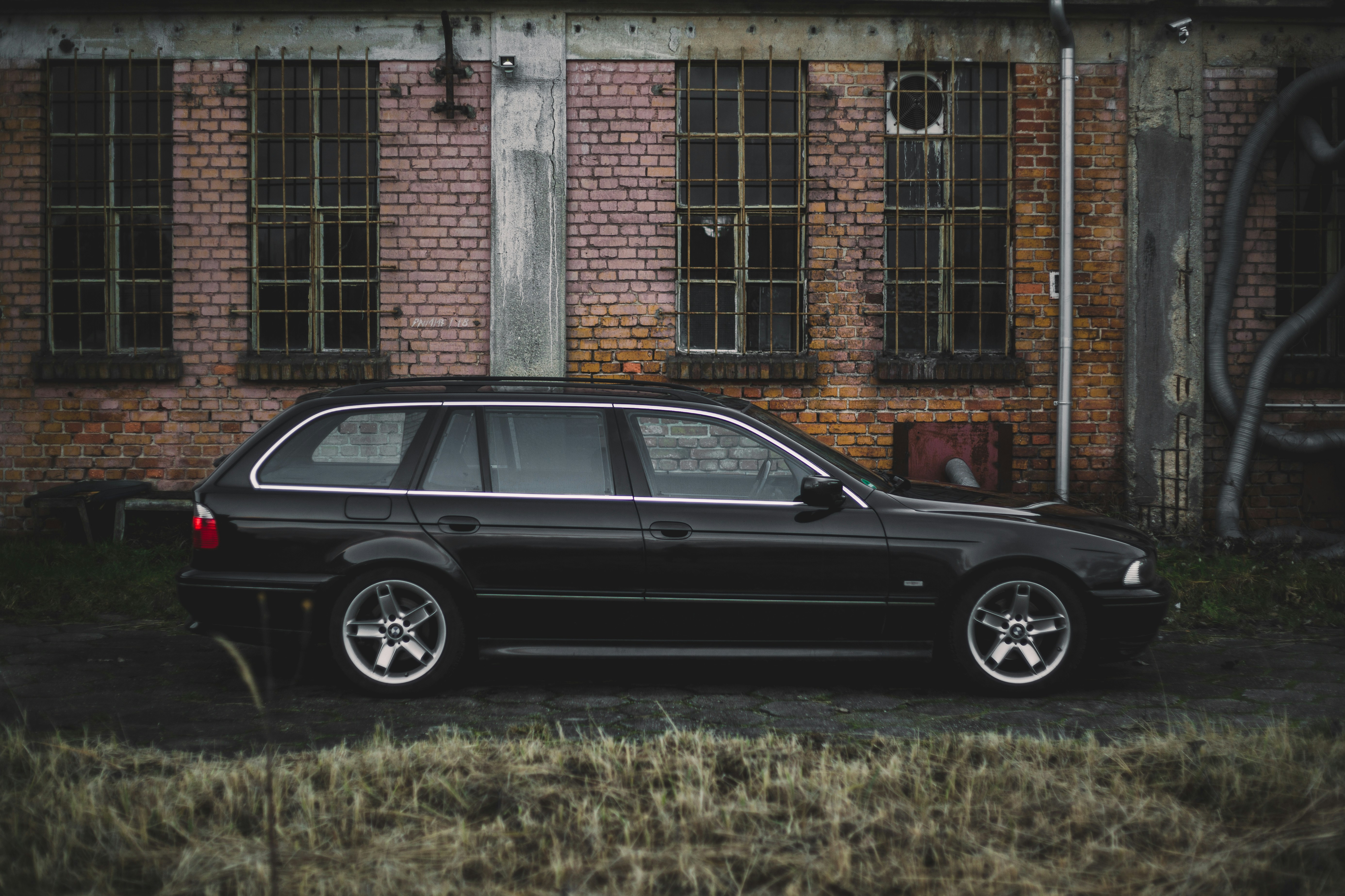 Ein schwarzes Auto parkt vor einem Backsteingebäude