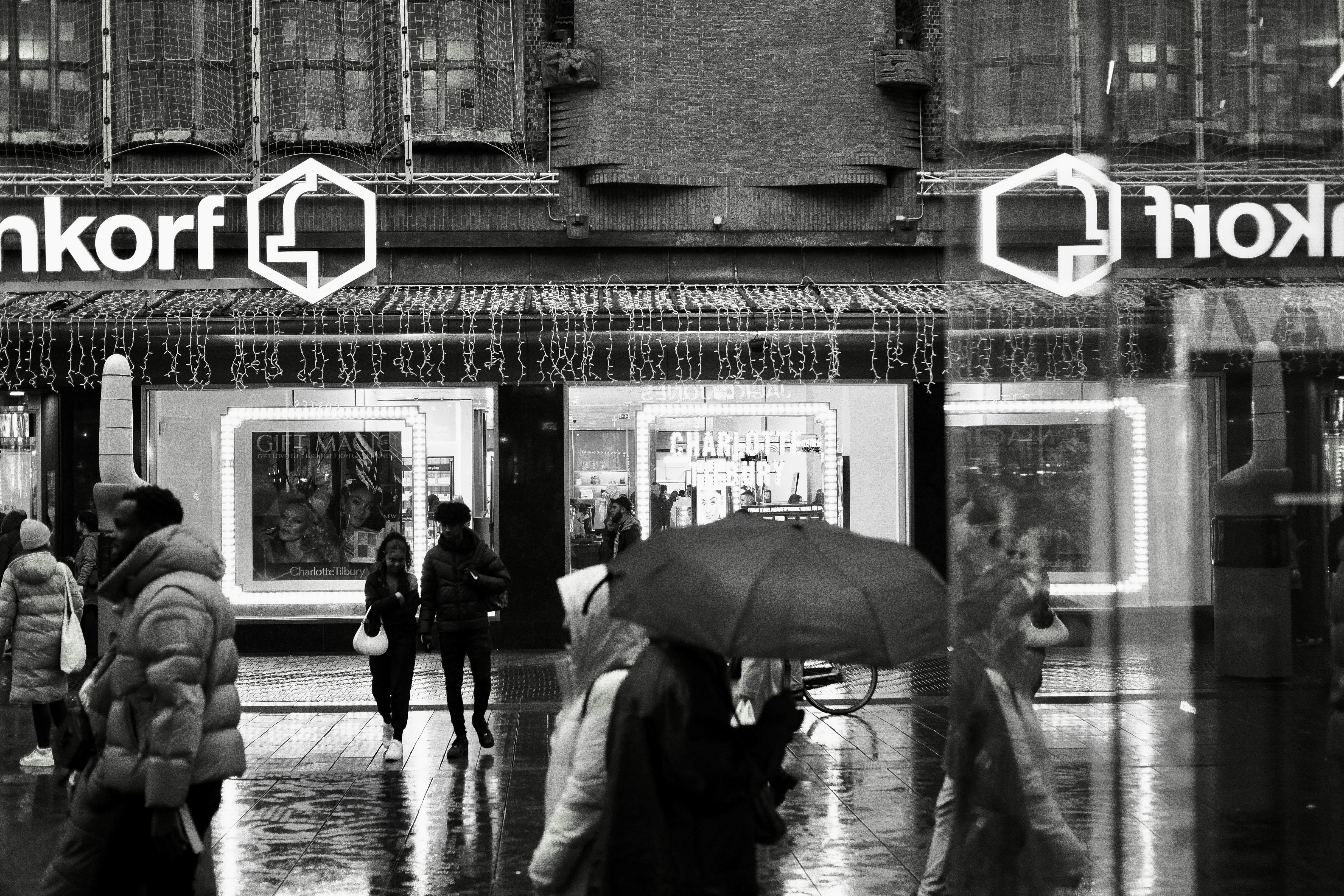 a black and white photo of people walking in the rain