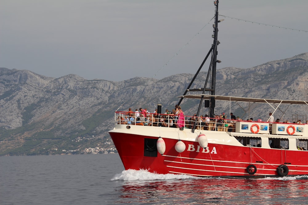 a red and white boat with people on it in the water