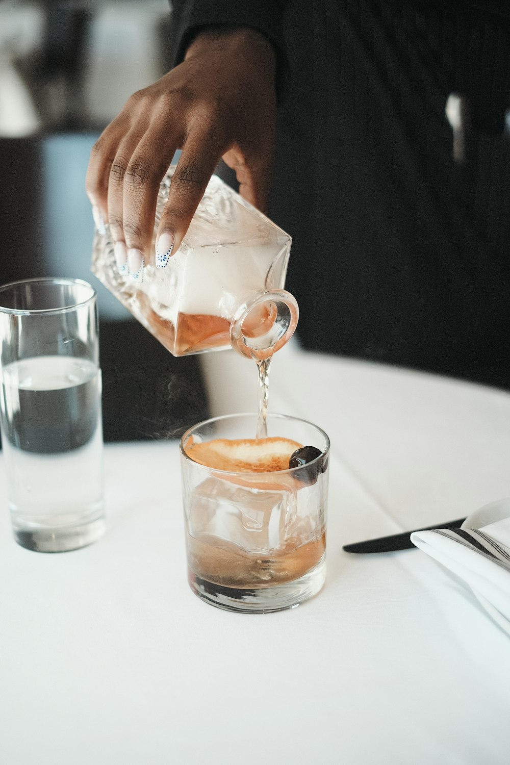 a person pouring a drink into a glass