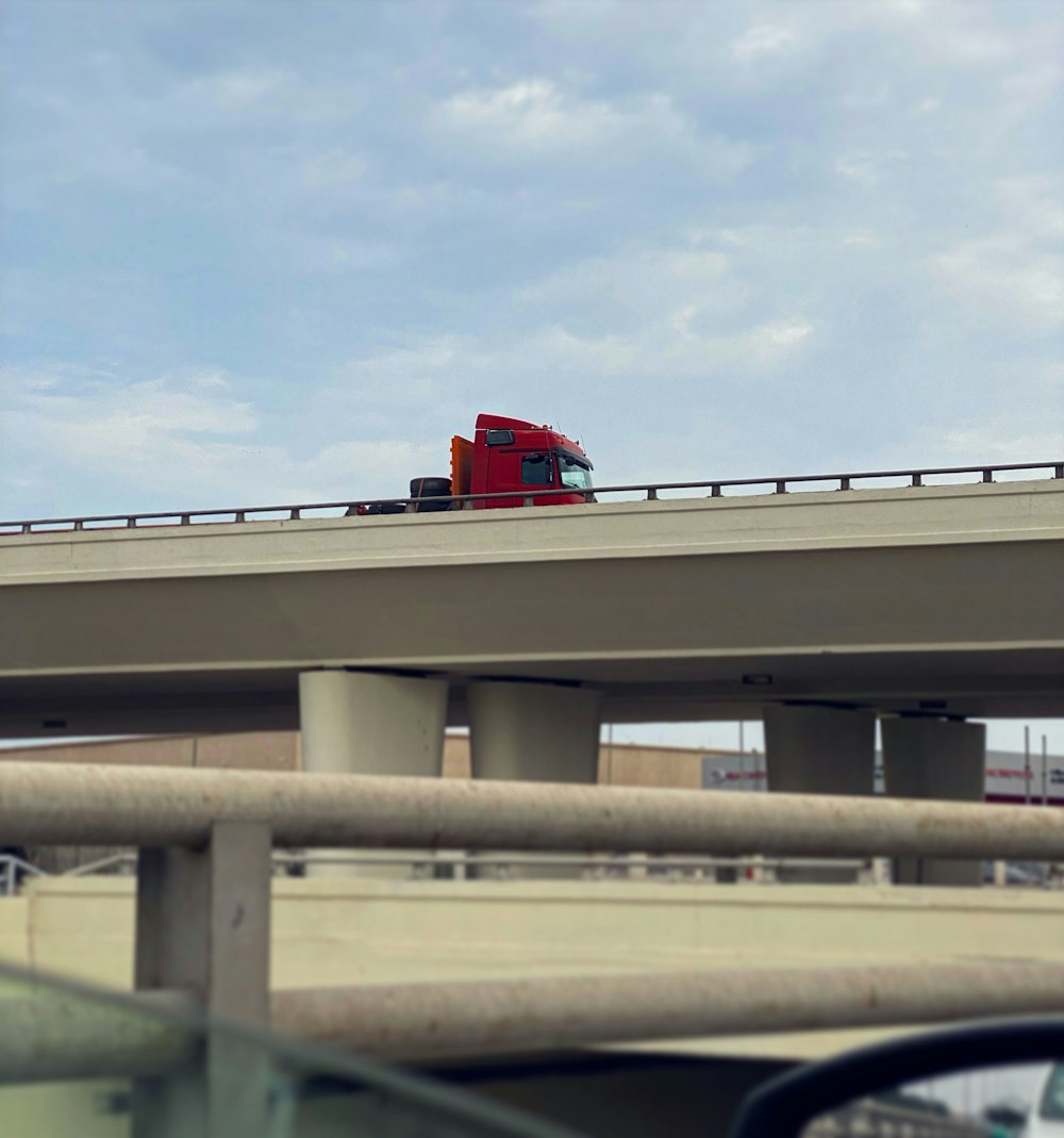 a red truck driving down a highway next to a bridge