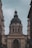 A large, ornate building with classical architecture, featuring a prominent, dark-colored dome. The facade is adorned with columns and detailed sculptures, including a depiction of religious scenes above the entrance. The inscription 'EGO SUM VIA VERITAS ET VITA' is visible across the archway.