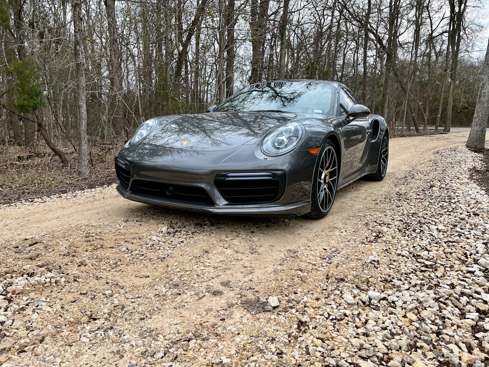 a black sports car parked on a gravel road