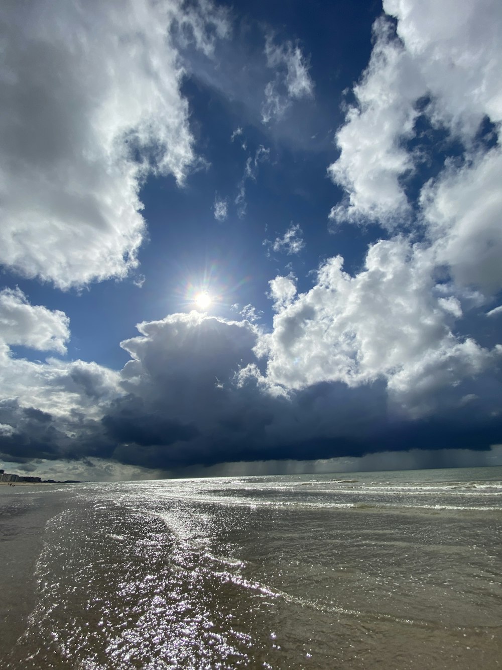 the sun shining through the clouds over a beach