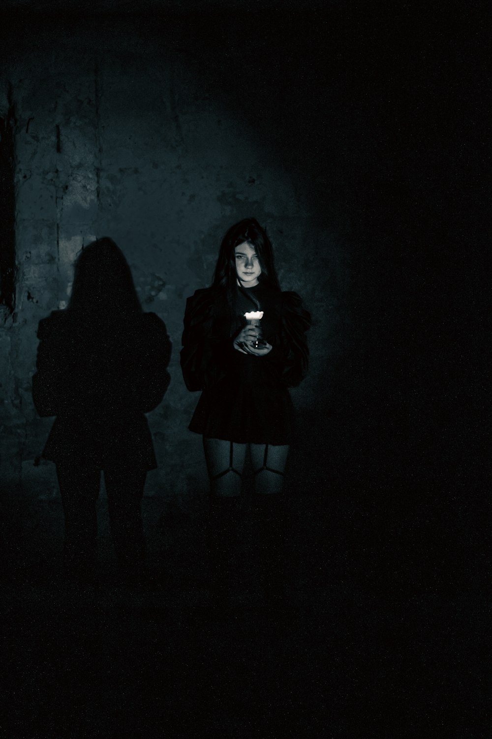 Una donna in piedi nel buio con in mano un telefono cellulare