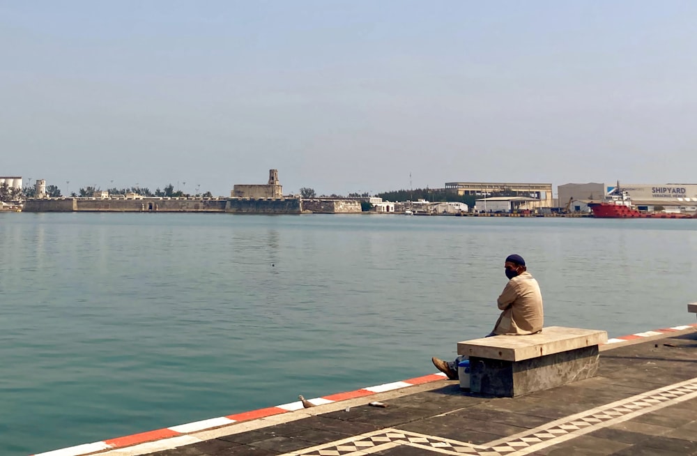 a man sitting on a bench near a body of water
